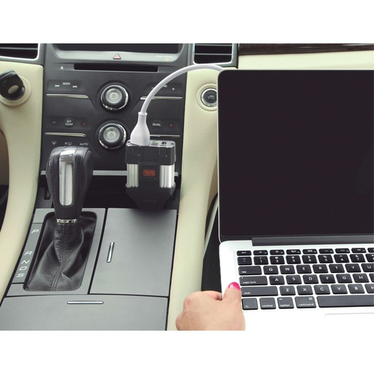 BLACKDECKER PI100LA car power inverter plugged into console outlet, charging a laptop, interior view.