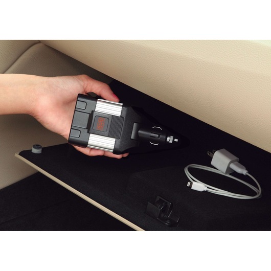 Photo of BLACKDECKER PI100LA car power inverter in glove compartment, person holding it, with USB charger cable.