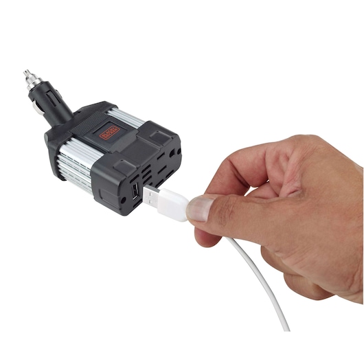 BLACKDECKER PI100LA power inverter with USB ports, hand plugging in USB cable, car adapter, front angle.