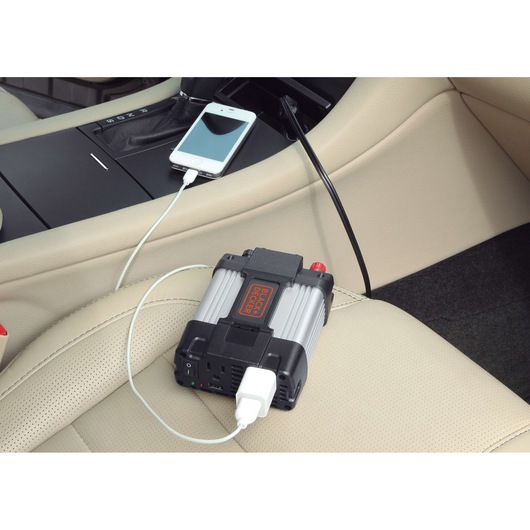 BLACKDECKER PI400LA power inverter charging a smartphone in a car interior on beige leather seat.