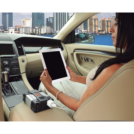 BLACKDECKER PI400LA power inverter charging a tablet in a car interior, urban skyline outside window.