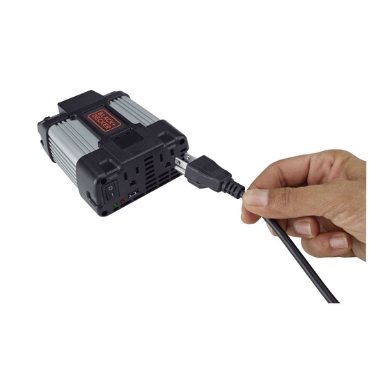 Photo of BLACKDECKER PI400LA power inverter with a hand plugging in a power cord, white background, angled view.