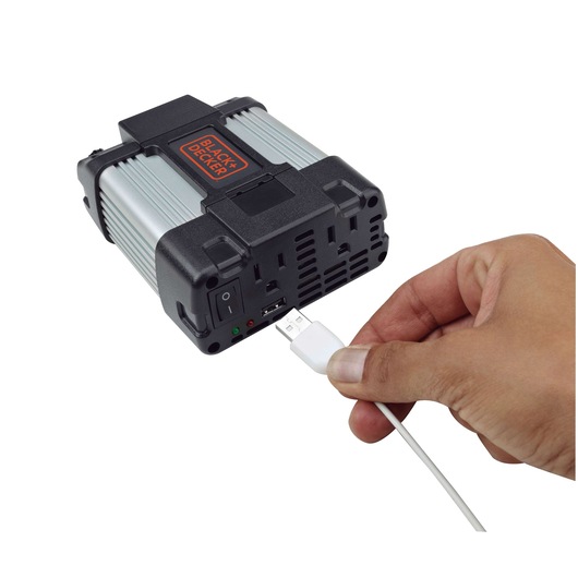 BLACK+DECKER PI400LA portable power inverter with a hand plugging in a USB cable, front angle.