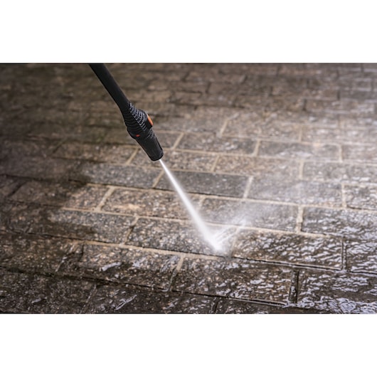 BLACKDECKER PW1450TD pressure washer nozzle cleaning wet stone pavement, close-up angle.