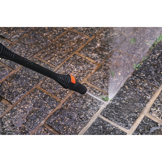 BLACKDECKER PW1450TD pressure washer spraying water on outdoor stone tiles.