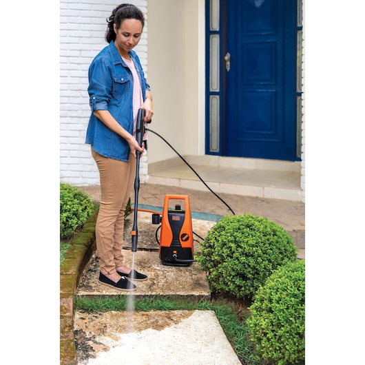 BLACKDECKER PW1450TD pressure washer cleaning outdoor stone path, garden setting, product in use.