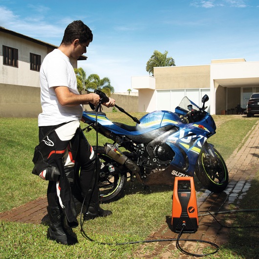 BLACKDECKER PW1450TD pressure washer cleaning blue motorcycle in driveway, outdoor setting.