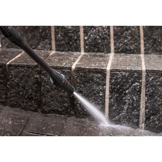 BLACKDECKER PW1450TD pressure washer spraying water on dark stone steps.