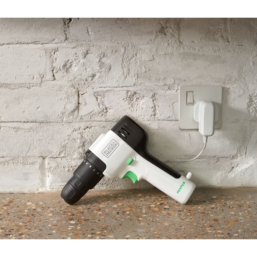 BLACKDECKER REVHD12C cordless drill with black and white design plugged into a wall socket, side view.
