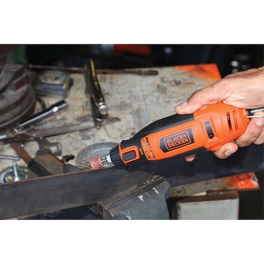 BLACKDECKER RT18KA rotary tool sanding metal on workbench, orange and black handheld power tool.