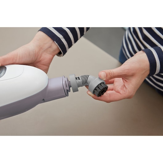 BLACKDECKER VL1300 handheld steam cleaner with a gray brush attachment being installed, close-up view.