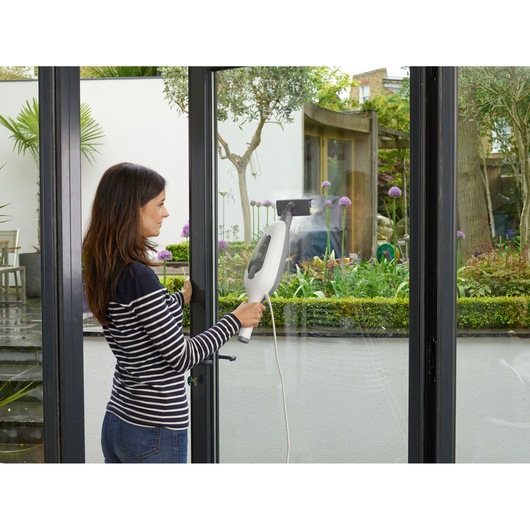 BLACKDECKER VL1300 window cleaner being used on a glass door indoors.