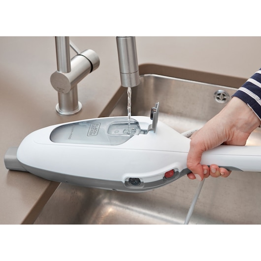 BLACK+DECKER VL1300 steam mop water tank being filled at a kitchen sink, close-up view.